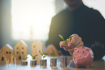 Hand hold Coins and pink piggy with icon business with Mini wood house model from model on wood...