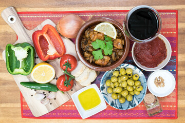 Mediterranean food - cooked meat, olives, yogurt, vegetables,  olive oil, wine - on a wooden table
