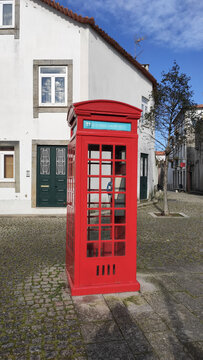 Fão, Esposende, Portugal - January 10, 2021: Old bright red public telephone booth in the street in Fao.