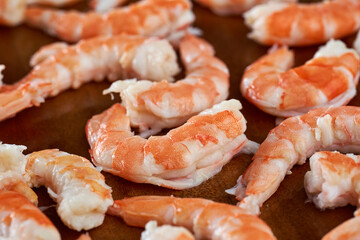 Unshelled red prawns on wooden board