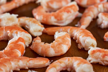 Unshelled red prawns on wooden board