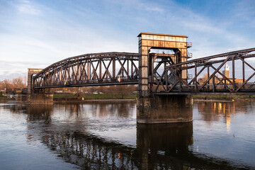 Obraz premium abandoned railway bridge over river at sunset