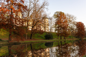 Fototapeta na wymiar autumn foliage at sunset with reflections on water in park