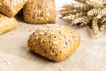 Rustic rye. Fresh loaf of rustic traditional bread with wheat grain ear or spike plant on linen texture background. Bakery with crusty loaves and crumbs. Design element for bakery product label.