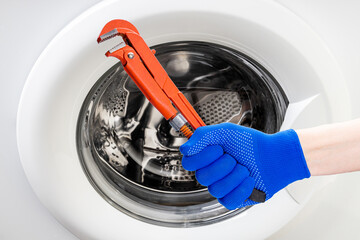 washer repair service concept. technician worker holding work tool in front of broken washing machine