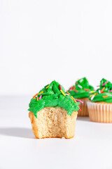 Green frosted vanilla cupcake with rainbow sprinkles on a white background