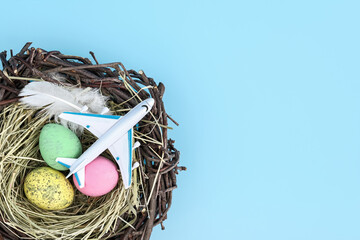 Top view of airplane and easter egg nest flatlay. Spring season travel concept background. Copy...