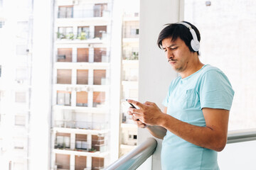 Fototapeta na wymiar Young Latino listening to music on the balcony of his house