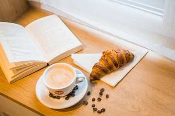 Cup of coffee and croissant and book
