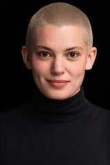 Young urban with short blonde hair poses before a black backdrop.