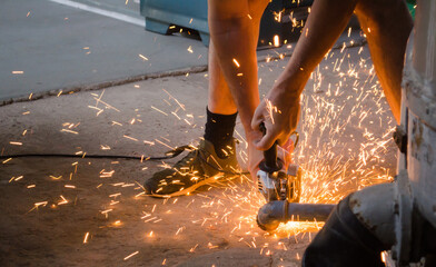 Man using grinder machine and throwing sparks to cut metal.