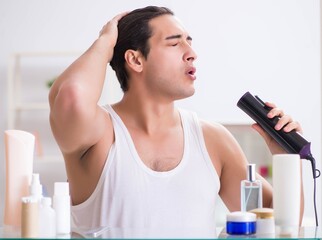 Young man drygin his hair in the morning