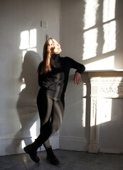 Woman standing indoors with shadows and sunlight effects