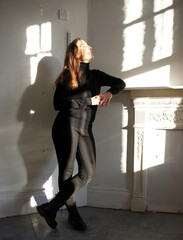 Woman standing indoors with shadows and sunlight effects