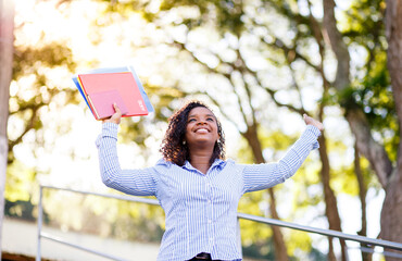 Naklejka premium Student girl celebrating and having fun. Happy girl with arms raised with trees in the background of the image.