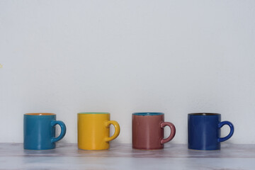 four cups of different colors arranged in a line available to write in them a four-letter word and also white space available above