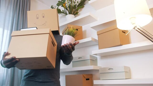 Excited black man with carboard box over his head relocating to new home. High quality 4k footage