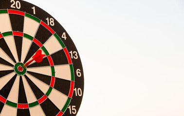 Obraz premium Dart arrow hit to center on bullseye(bull's-eye) of a dartboard is a target of purpose challenge business at sunset, expert strategy market target, objective financial and goal a concept