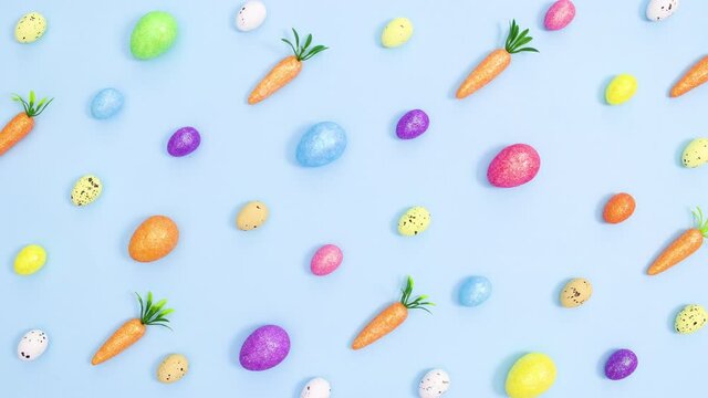 Creative Easter vibrant pattern made of eggs and carrots on pastel blue background. Stop motion flat lay