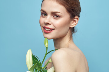 Woman with white flower on blue background cropped view of naked shoulders