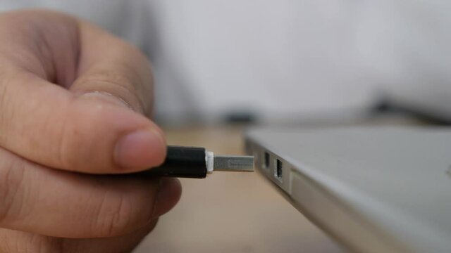 Person inserting plug in flashdisk into usb port in laptop personal computer, data transfer device concept