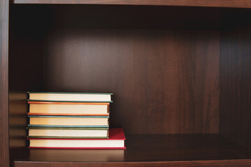 A stack of books placed on one side of the shelf; Empty space beside a pile of books