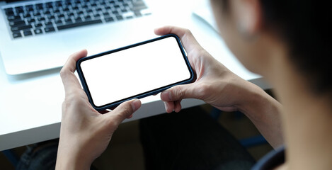 Close up view of male hands using smart phone with modern office blurred background. Blank screen monitor for graphic display montage.