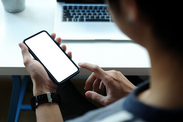 Close up view of male hands using smart phone with modern office blurred background. Blank screen monitor for graphic display montage.