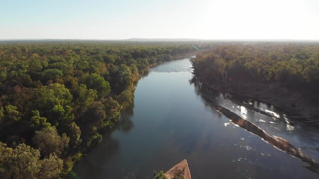 Aerial view of a large river in the middle of lush forest with glittering water, Australian outback, Darwin, Australia