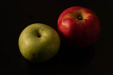 two apples green and red on black