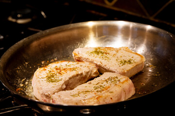 Rosemary seasoned pork loin cuts  searing in a pan; Golden crust on pork loin seared in a pan