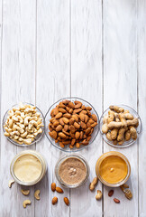 The modern concept of wellness and veganism. Jars of almond, cashew and peanut butter on a white wooden table. Organic, homemade nut butter for a healthy breakfast.
