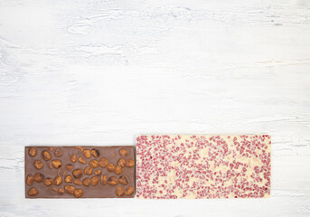 different sweet, delicate chocolate bars lie creatively on a white wooden background