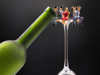 miniature people. alcohol addiction problem concept. alcoholics are in a wine glass against the background of a bottle.