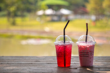 iced Pink milk, Thai style iced sweet milk with cider syrup and iced red water  on the wooden table in the peaceful coffee shop.