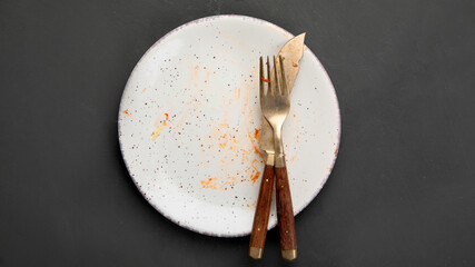 Pile of empty and dirty plates with food leftovers on dark background.