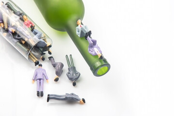 miniature people. figurines of people alcoholics in a wine glass and against the background of a...