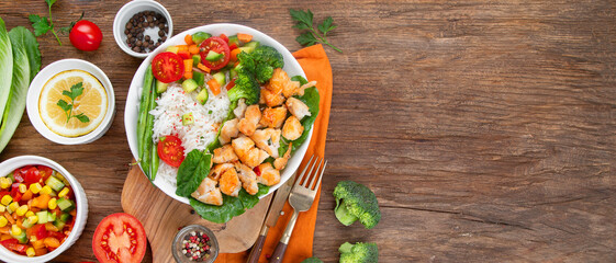 Delicious healthy homemade chicken and rice diner with fresh vegetables on wooden background