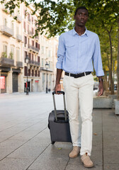 Portrait of an african american tourist on the street of european city with suitcase