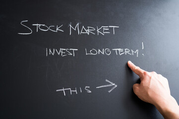 "Invest long term in the stock market" written in chalk on the black board