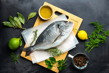 Fresh borabo fish with ingredients for cooking on dark background top view. Delicious and healthy food