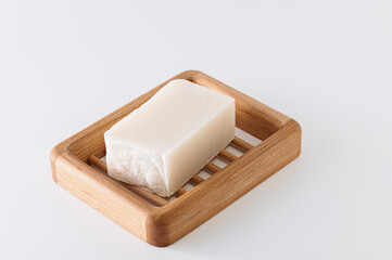 natural handmade soap on a wooden soap dish, side view, on a bath towel, light background