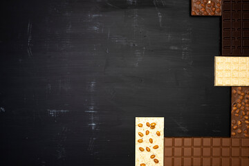 a lot of different sweet, delicate chocolate bars lie creatively on a black wooden background