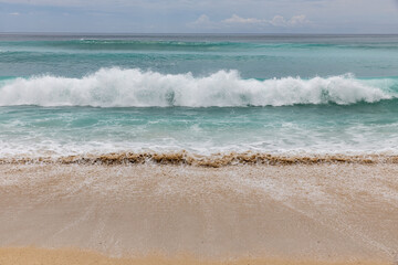 Seascape background. Sandy beach, milky foam waves, blue ocean. Scenic waterscape. Horizon line. Nature and environment concept. Daylight. Copy space. Dreamland beach, Bali