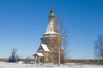 Birch and old wooden Sreteno-Mikhailovskaya church (1655) on February afternoon. Krasnaya Lyaga, Kargopol district. Arakhangelsk region, Russia