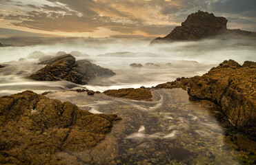 Long exposure water, beautiful seascape, ocean views, rocky coastline, sunlight on the horizon. Composition of nature. Sunset scenery background. Cloudy sky. California coast.