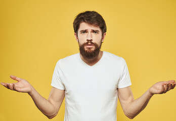 Brunette man gesturing with his hands on yellow background cropped view