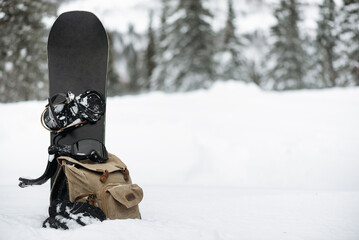 Snowboard, snowboard goggles and backpack on the snow. Snowboarding background.