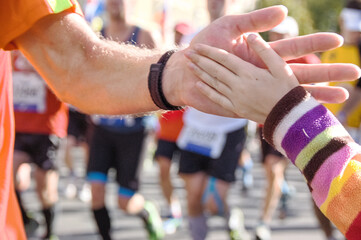 Marathon running race, supporting runners on road, child hand giving highfive, sport concept
