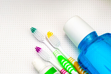 three colorful toothbrushes a tube of toothpaste and a mouthwash lie on the bathroom table close up